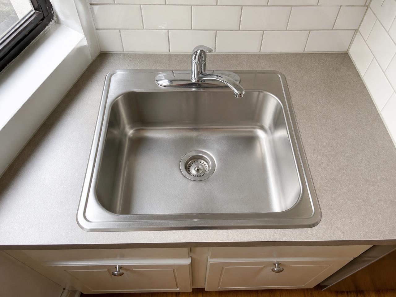 Spotless kitchen sink with the ScrapCatch scraper resting on the edge